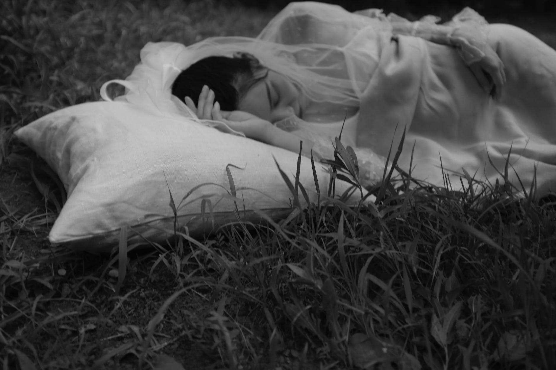 grayscale photo of woman lying on grass field